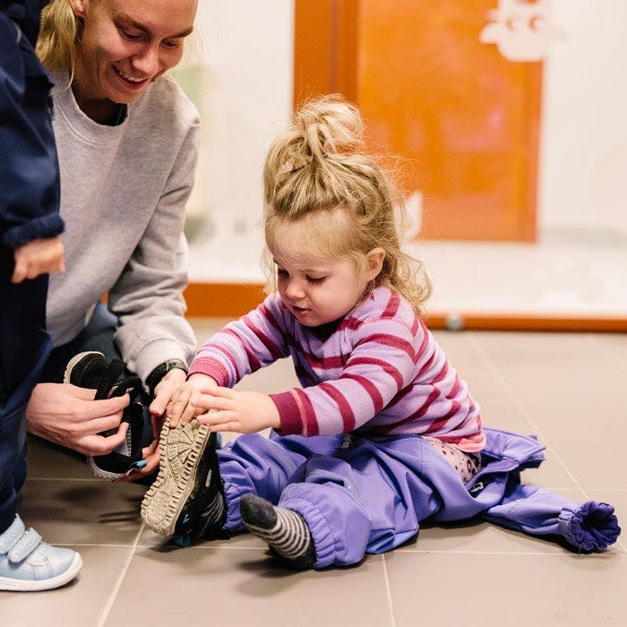 Barn tar på sko med hjelp fra en voksen